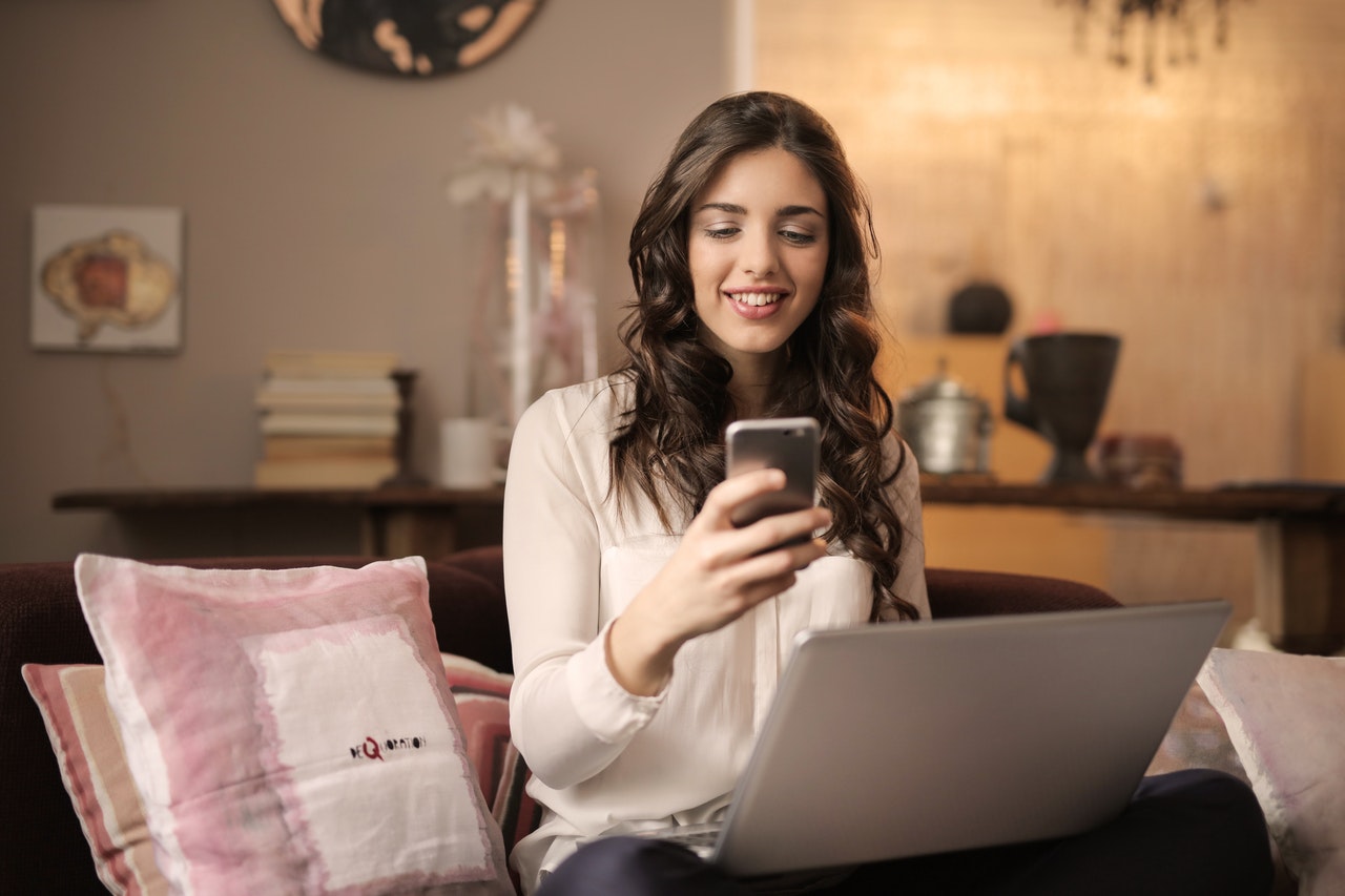 Girl Sitting on Bed Using Laptop And Smartphone